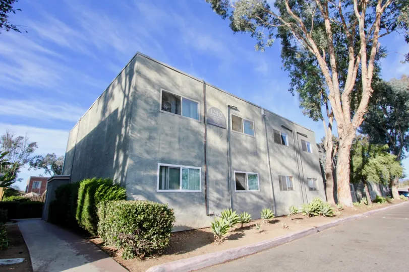 Grey Apartment building in Villa La Paz, in Escondido, California. Building is rectangular, with some bushes and plants in front.