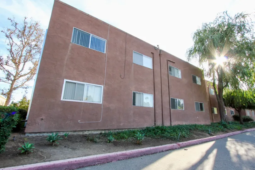 Reddish building surface on the side of the road with multiple windows, located in Villa La Paz, in Escondido, California.