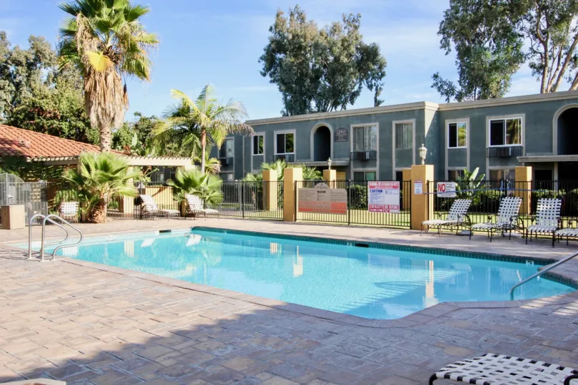Villa La Paz community Escondido California pool lounge chairs fence gray arched entry windows covered entrance palm trees landscaping