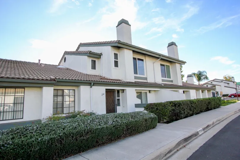 Modern two story house with shingled roof, hedges and sidewalk, located in Westwinds I, Escondido, California.