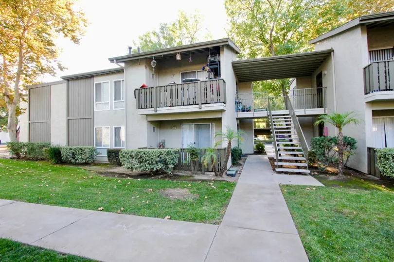 White Oak Estates in Escondido California gray two story apartments with lawn palms and walkway