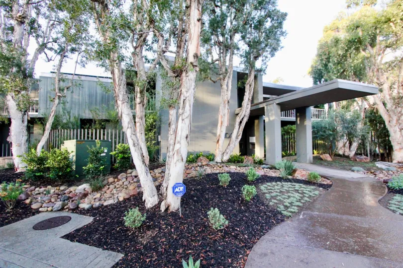 THE GREENY HOUSE IN THE 3100 FRONT WITH THE PATHWAY, PLANTS, TREES, ELECTRIC BOX, BALCONI