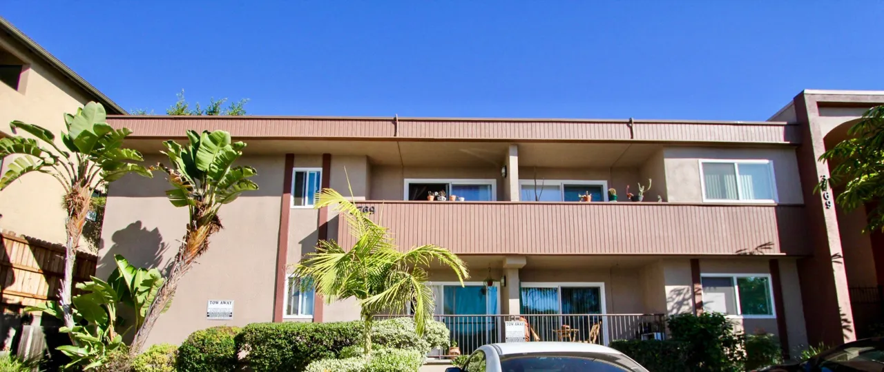 Car is parking in front of the 3769 1st Ave apartment with bushes and plants