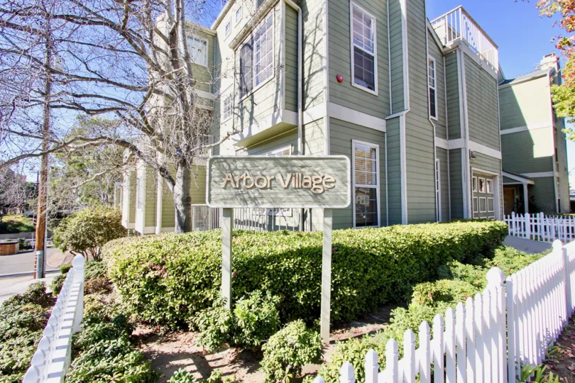 Corner unit with white picket fence, trimmed hedges and traditional style architecture at Arbor Village