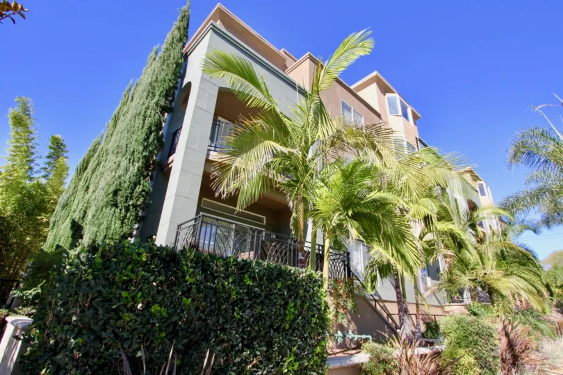 A low-rise housing unit with plenty of tall greens in the Centre Court Condominiums community.