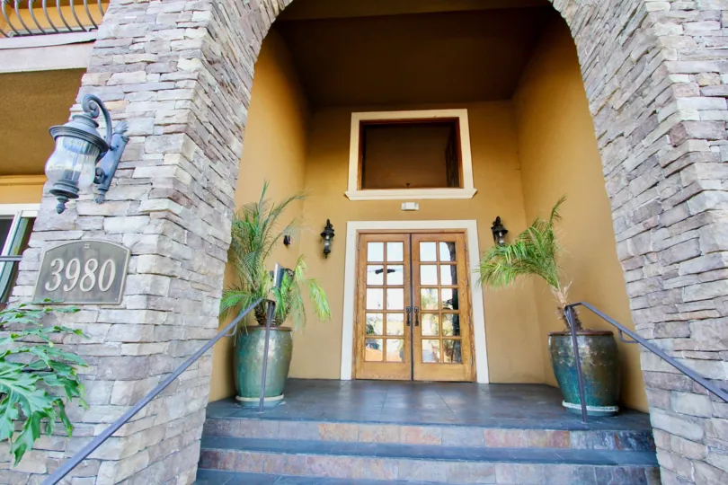 grsnd entrsnce with stone collumns and woody look and brown walls and plants