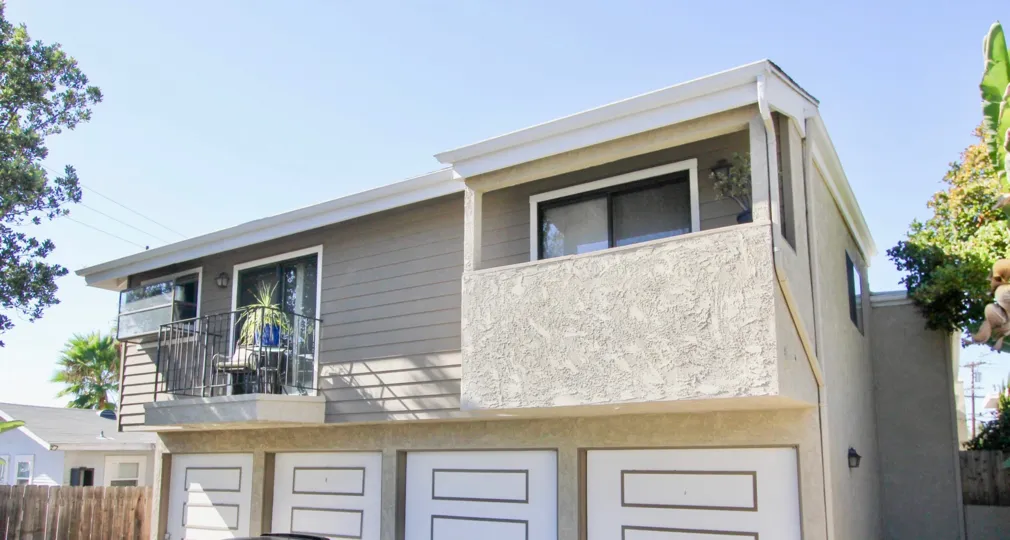 The exterior of a quant unit at the Condos at 4130 Cleveland with four private garages, two private balconies, and a portion of the privacy fence.