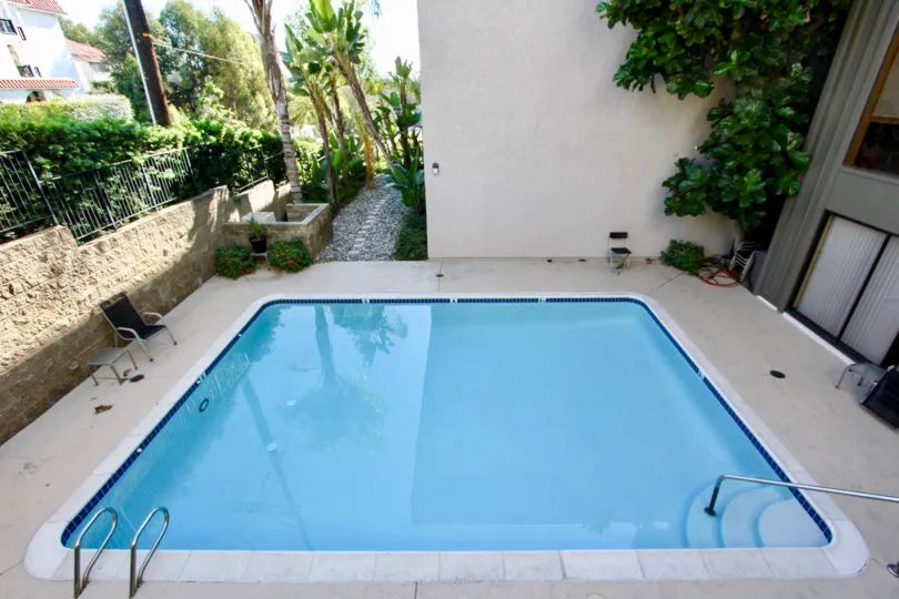 Decent sized wading pool with high privacy walls and fences with additional hedges and a flagtone lined pathway in Hillcrest