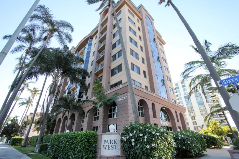 The exterior of a high-rise complex at the corner of Sixth in thr Park West section of Hillcrest, CA with landscaped shrubs, flowers and palms.