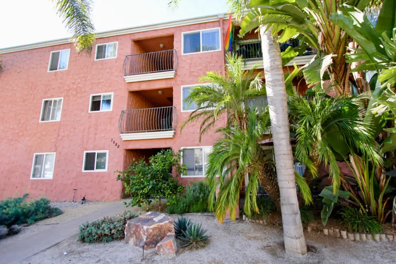 The Building painted in red and has trees and plants in Terrace Village