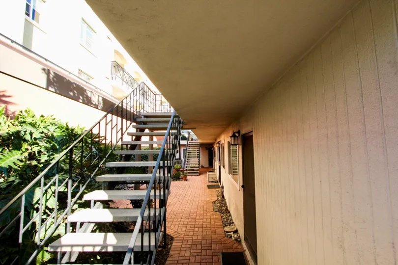 Open riser staircase, hedges and inlaid brick floor lined with gravel at The Orleans
