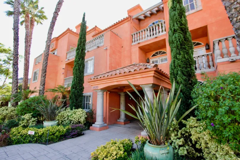 a grand building that has orange paint job all over with hints of white and lush greenery around