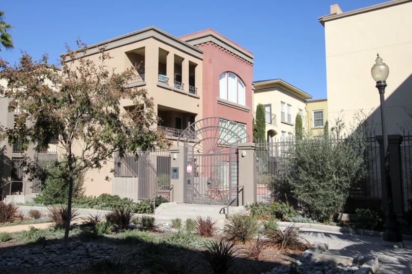 Outside the gate of the apartment has plants, light lamps and bushes in dry sand