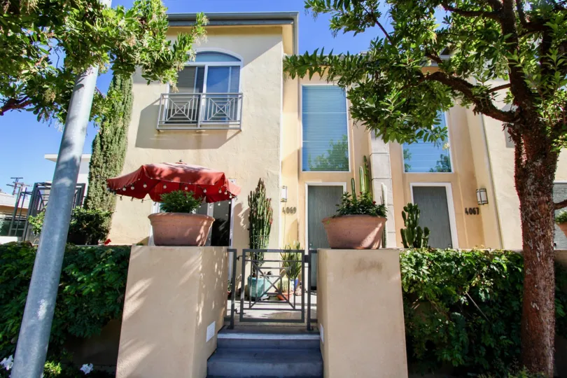 Wellington Square beige two-story with gate and trees Hillcrest California