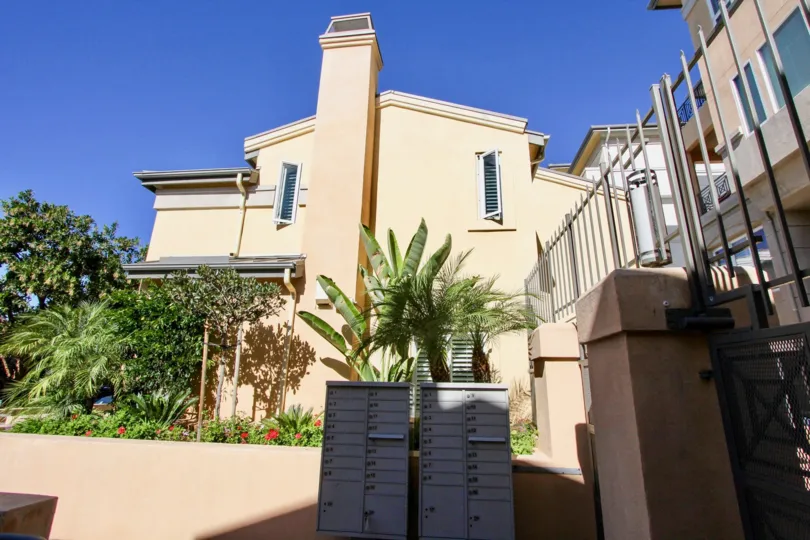 Community mailboxes and gated entryway with high security fences ringed by ample gardening in Hillcrest