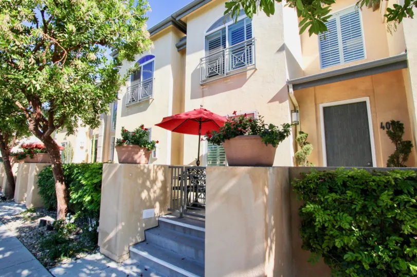 A view of a patio with bright red umbrella and flowers at Wellington Square California