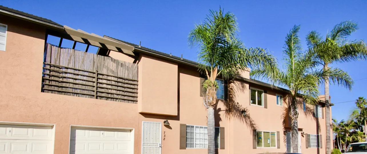Colorful apartment building with nice palm trees in the middle of a nice day.