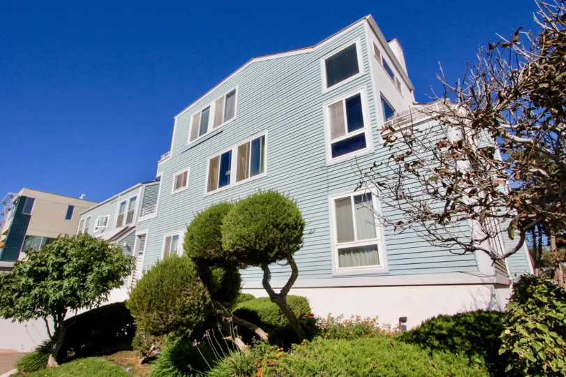 Three story residence with green lanscaping outside located at Coastwalk Townhomes.