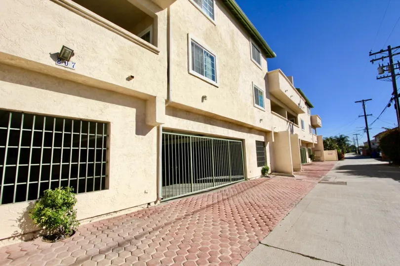 A row of houses with a wide pathway and some electric poles in front during a sunny day in Costa Del Mar II, Imperial Beach, CA