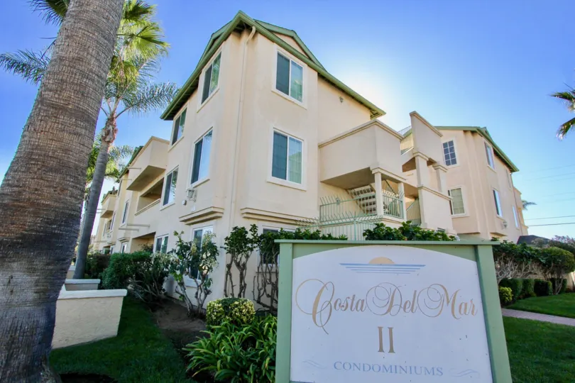 Three story housing behind community sign at Costa Del Mar II in Imperial Beach California