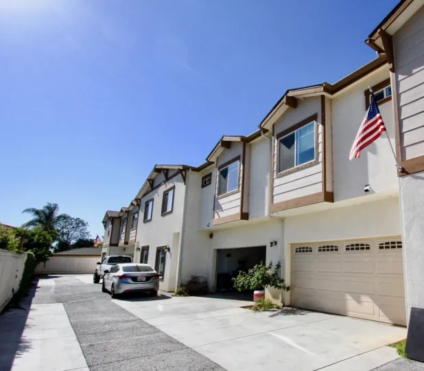 A row of houses with a long driveway and some parked cars during a sunny day in Holly Avenue, Imperial Beach, CA