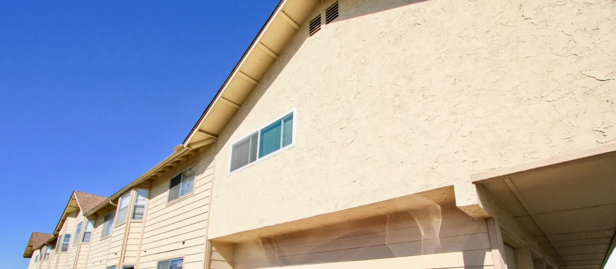 Top of beige building front with multiple windows, beige in color