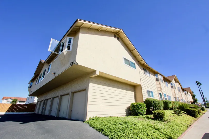 Two story housing with white garage doors near a green hillside in Holly Manor in Imperial Beach CA