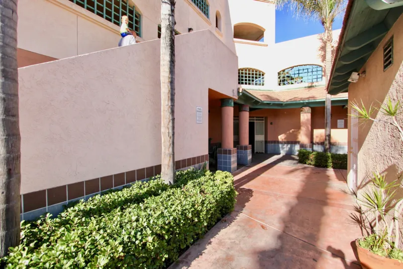 A corridor between two buildings with some landscaping in Imperial Beach Club