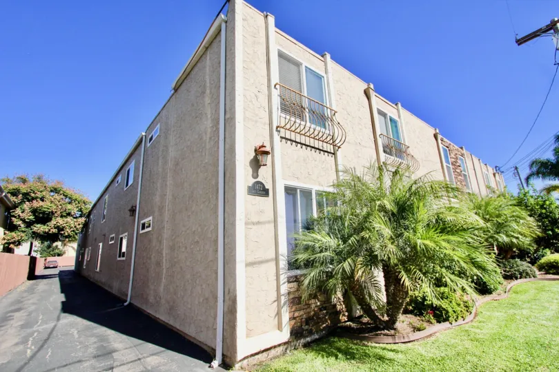 Two level white building with iron porch and palm tree in Iris Gardens