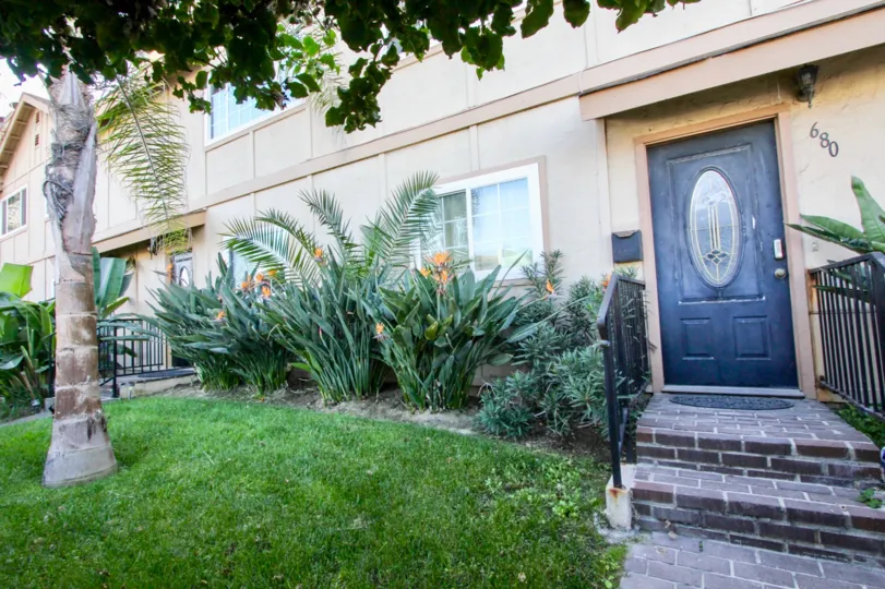 A villa in Ocean Villas West has a number 680 with plants, trees, grasses in a front view