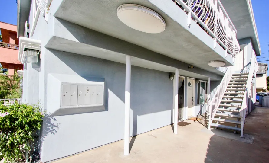 A gray apartment building with a white staircase during a sunny day in Shauna Shores, Imperial Beach, CA