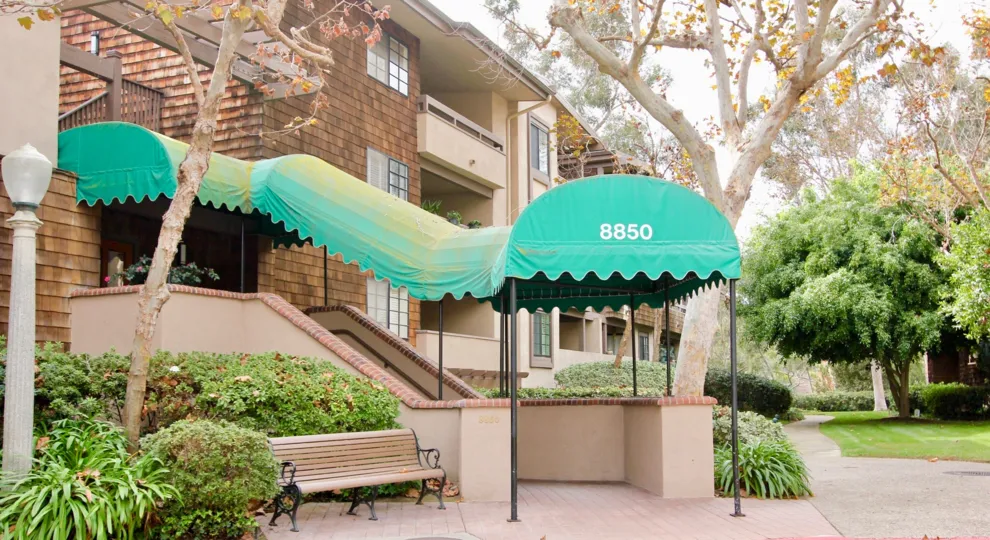 Three story brown residential building with green awning at Boardwalk in La Jolla CA