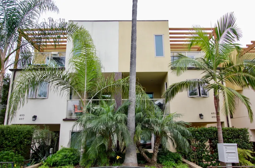 Three story building with a tall palm in front at Bonair Street Condos in La Jolla CA