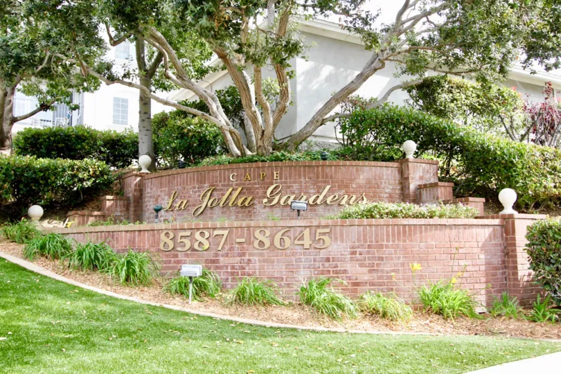 Golden community sign on a red brick wall at Cape La Jolla Gardens in La Jolla California