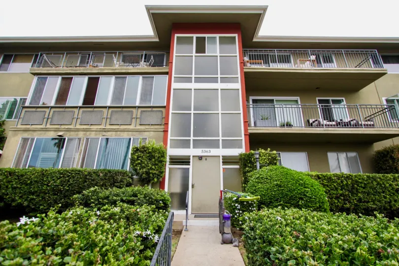 Apartment with two floors has glass doors and windows and has garden infront to the apartment