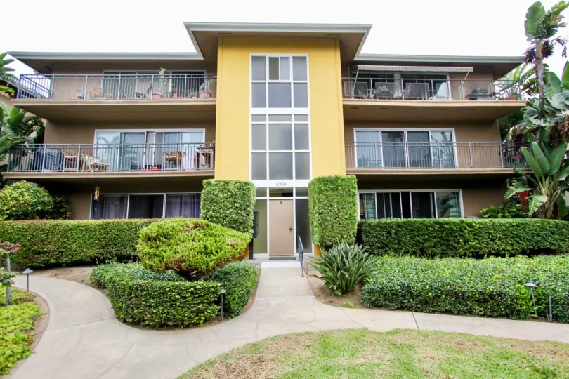 Yellow & brown units with shrubs inside Capri Aire in La Jolla CA