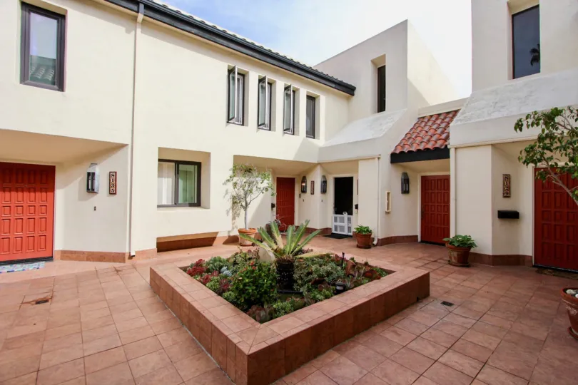 Red brick planter surrounded by white residence at Casa Del Grande in La Jolla CA