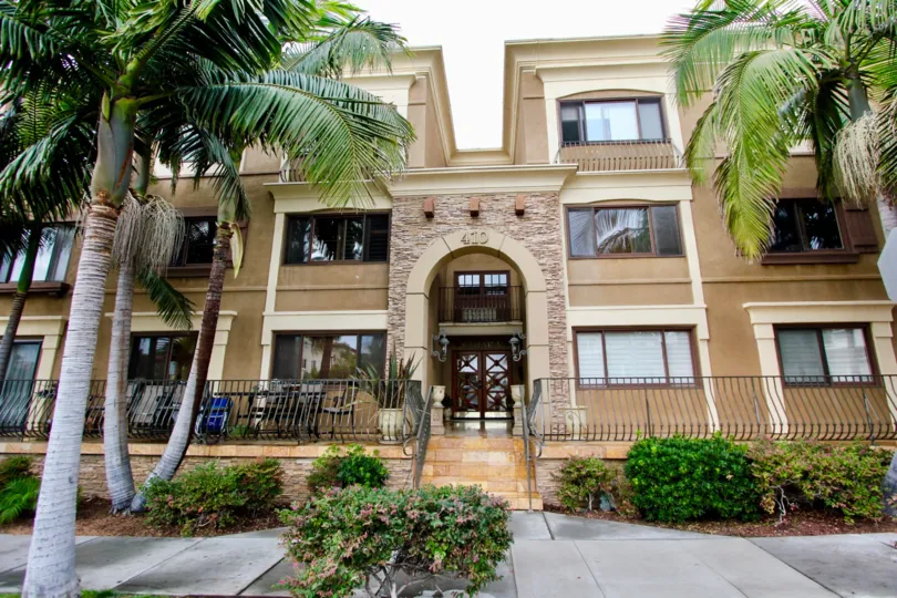 Three story residential building with gray railing and palms at Chiara in La Jolla CA