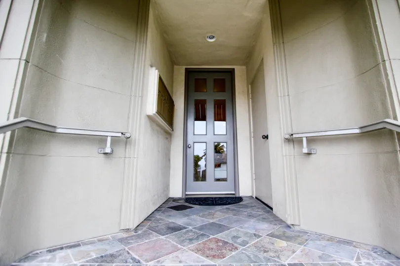 Glass and wood door with marble walkway at Coast Pointe in La Jolla CA