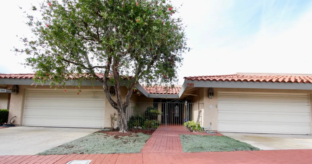 front view of two homes with a red brick walkway, garage and gate locking the two