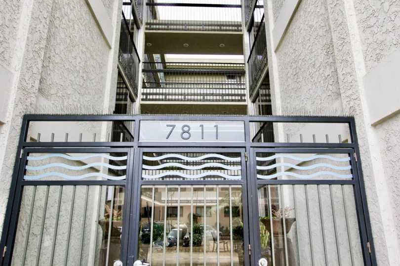 A gate with the street number and a view of the apartments in the back at Devonshire, La Jolla, CA