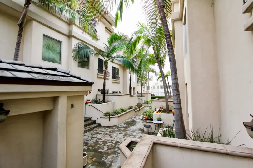 Walkway with garden area with trees at Draper Villas in La Jolla California