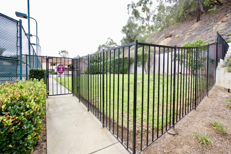 A lawn behind a black fence next to a sidewalk in La Jolla Hideaway