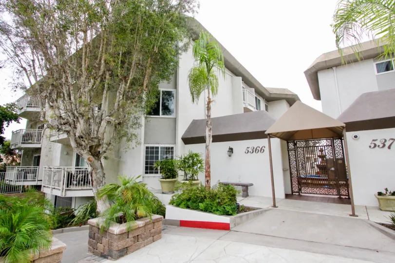 White condominiums with tall trees inside La Jolla Place in La Jolla CA