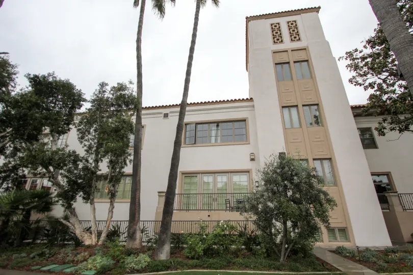 A very tall adobe building with architectural details and palm trees in La Jolla Prospect Condos