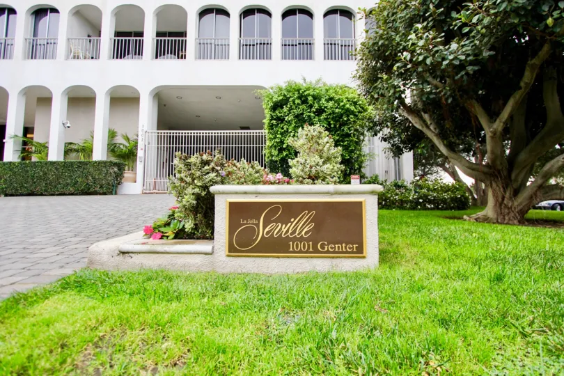 Gold and brown sign below a condominium high rise at La Jolla Seville in La Jolla CA