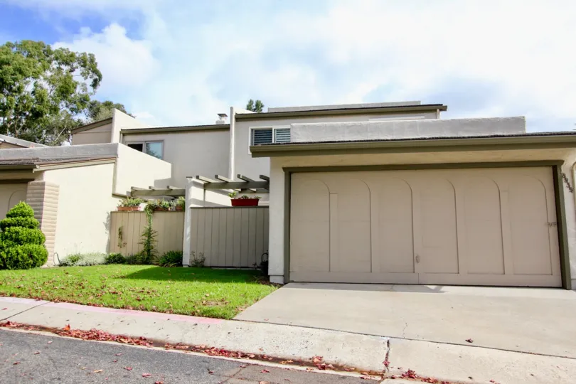 A blocky house with a big garage, well kept lawn and some bushes during a sunny day in La Jolla Shores Heights, La Jolla, CA
