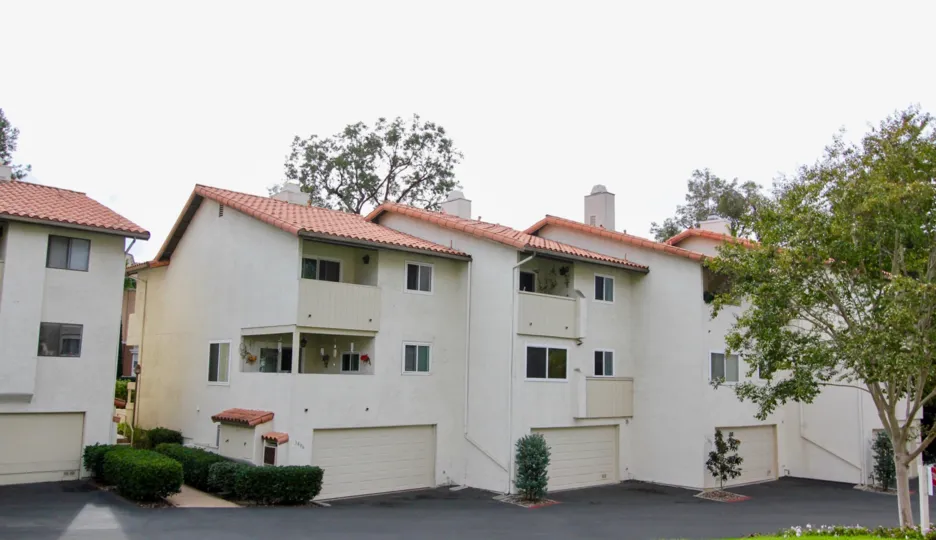 The Way of the house in the La Jolla Village tennis Club with bushes and trees