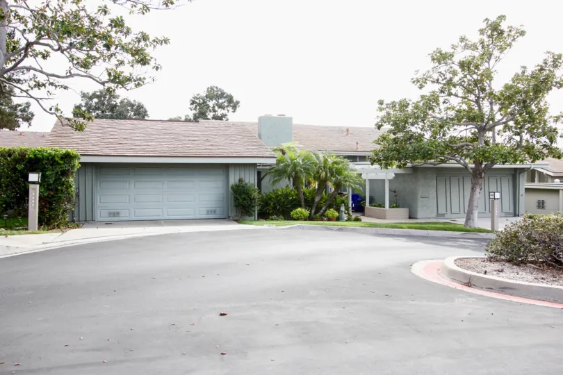 A gray one story ranch style home sits in front of a round driveway in the Mount La Jolla Community