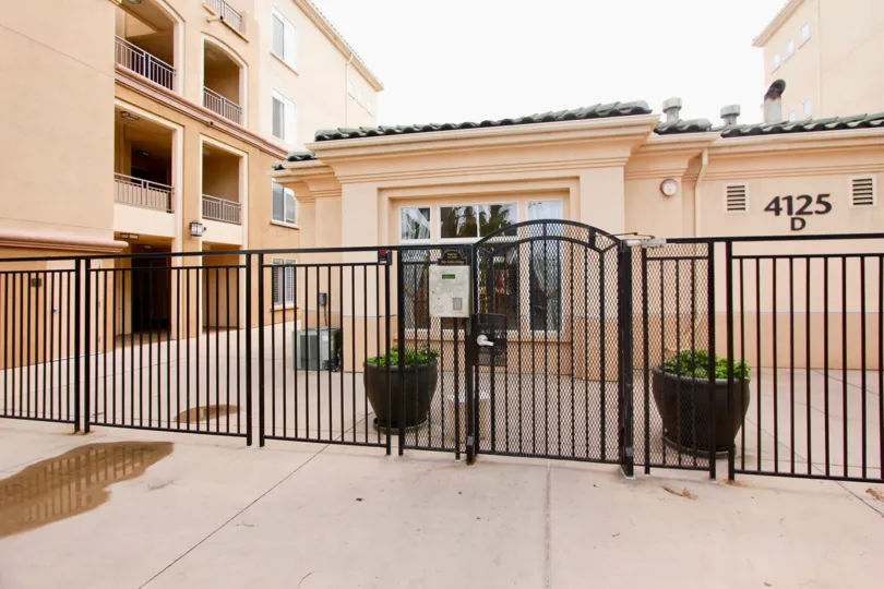 Black iron gate in front of a pink building in Regents La Jolla in La Jolla California